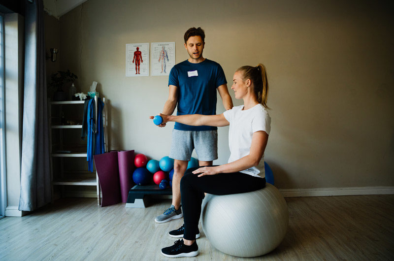 Male-physical-therapist-training-female-as-she-performs-therapeutic-exercises