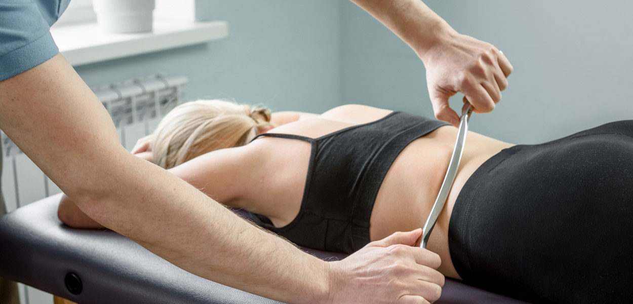 Physical-therapist-performing-Instruments-Assisted-Soft-Tissue-Mobilization-(IASTM)-on-female-patient’s-lower-back