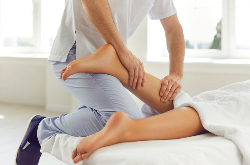 Therapist-offering-manual-physical-therapy-for-female-patient’s-calf-muscle